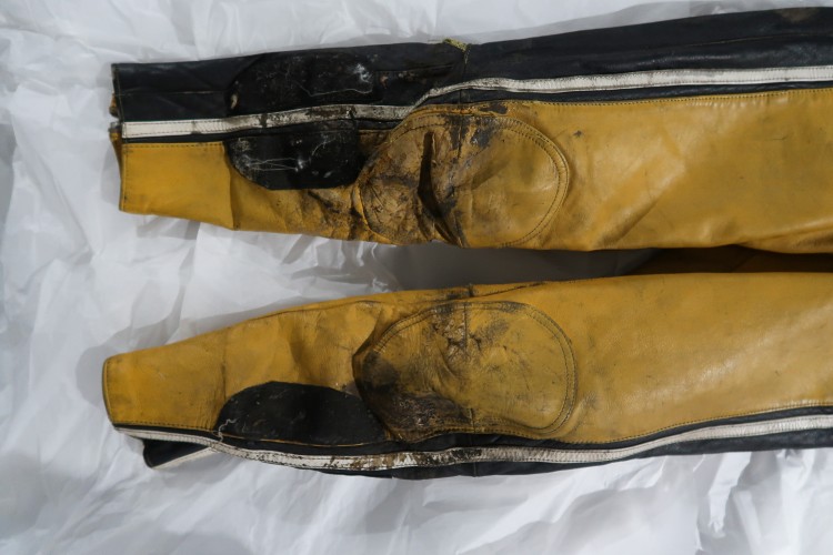 The legs of a yellow and black racing jumpsuit showing wear.