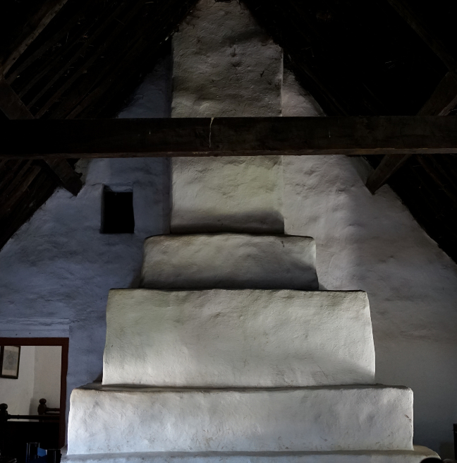 A large chimney breast stretches from floor to ceiling. It is white washed and tiered.