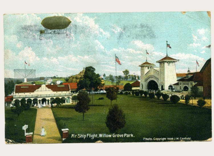 A postcard with a scene of a large park in America. An airship is in the sky.