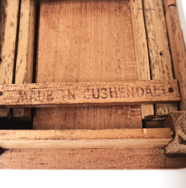 The underside of a table for a dolls' house. One of the beams is stamped 'MADE IN CUSHENDALL'