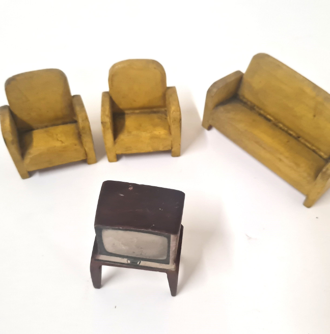 Dolls' house furniture, incluing two yellow armchairs, a yellow couch, and a television from the 70's or 80's.