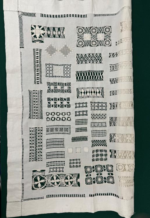 A sampler, white in colour, placed on a black background, of drawn thread work stitches c.1900