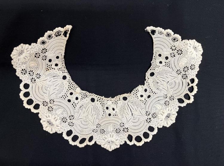 Detail of embroidery on a white dress collar from c.1860. It is placed on a black background