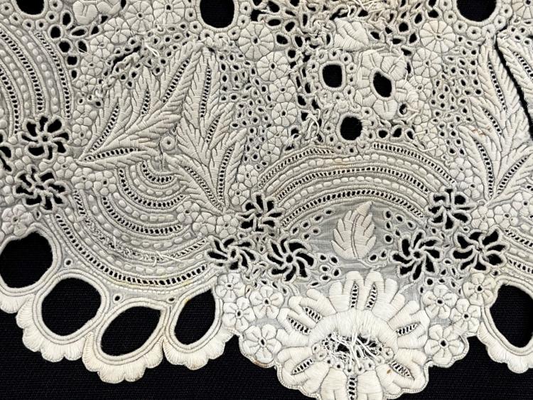 Detail of embroidery on a white dress collar from c.1860.  It is placed on a black background