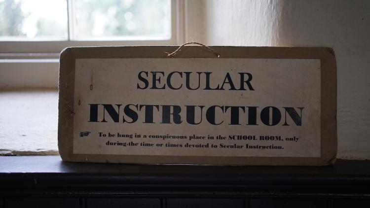 A sign in a schoolhouse that reads 'secular instruction'.