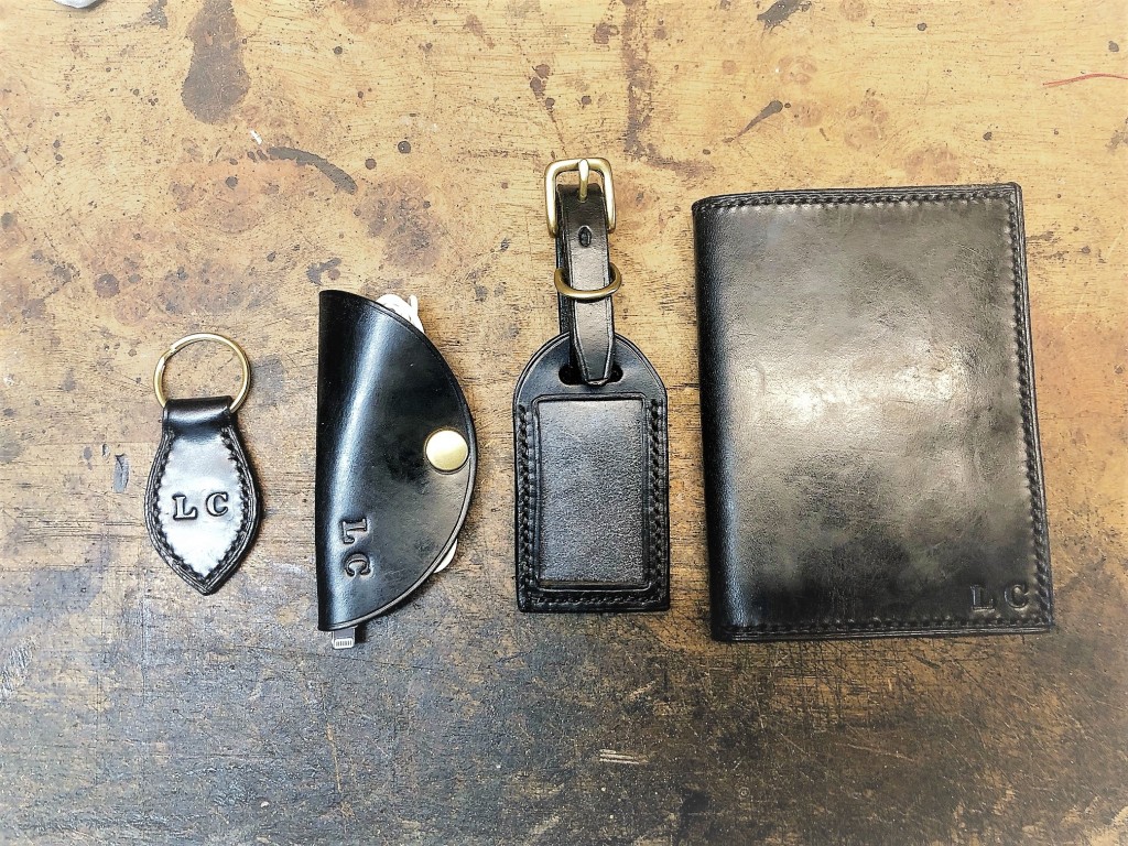 A keyring, passport holder, and luggage tag made of brown leather