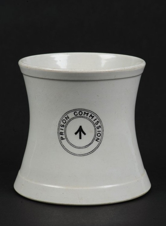 A white mug on a black background. The lettering on the mug reads, 'Prison Commision'.
