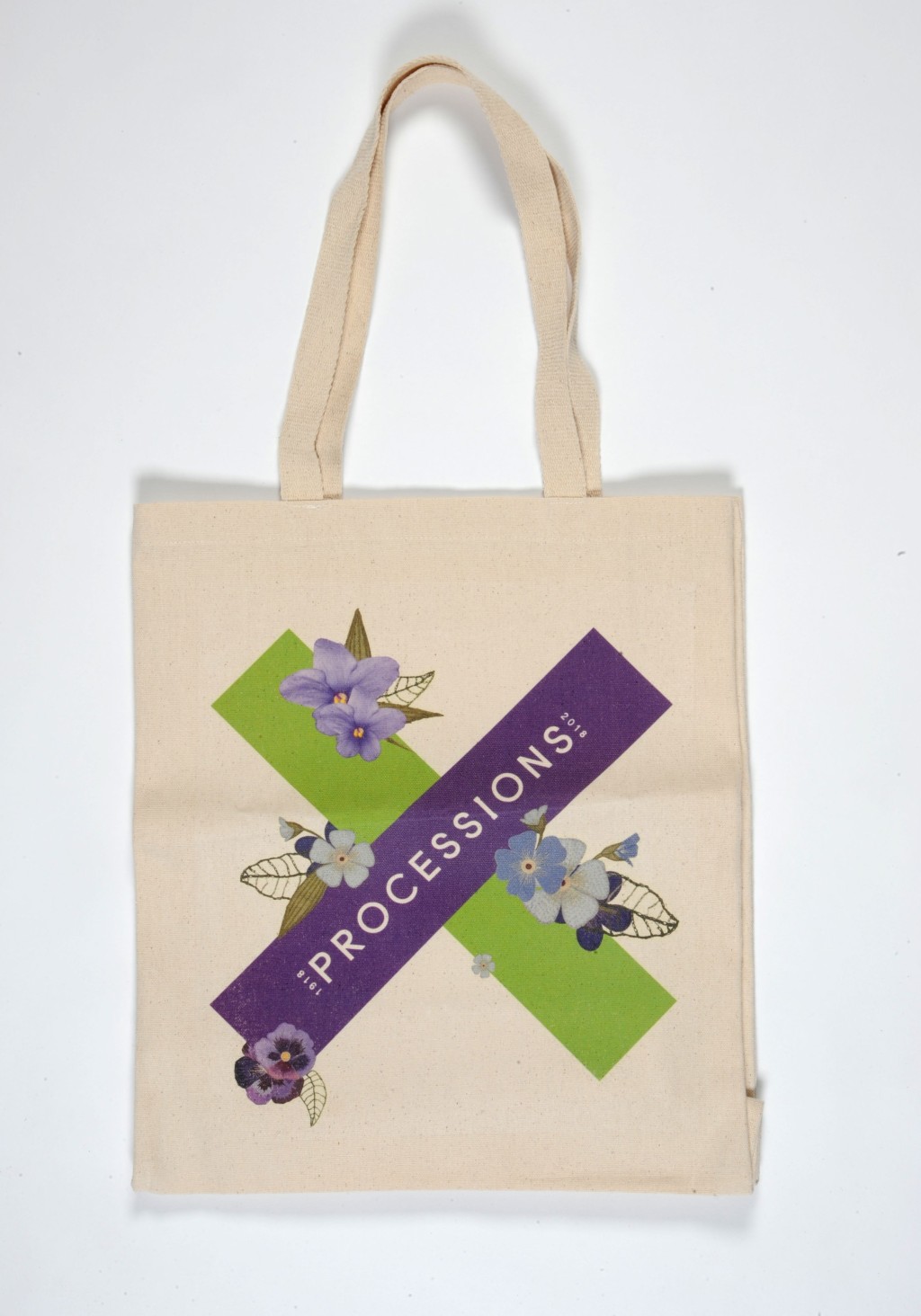 A tote back with a logo on it. The logo is a cross, one line of green and one line of purple. Purple and white flowers decorate the X, with green leaves. On the purple line of the X, 'PROCESSION' is written, resembling a sash.