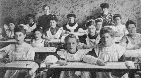 A black and white photograph c.1900s of girls in a classroom.