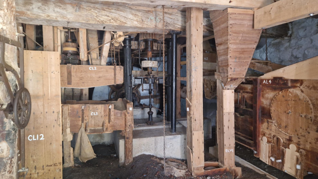 The interior of a corn mill, a small room with wooden contraptions.
